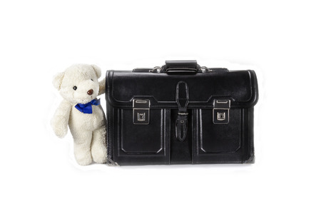 Black retro leather schoolbag with teddy bear on backgroundの写真素材
