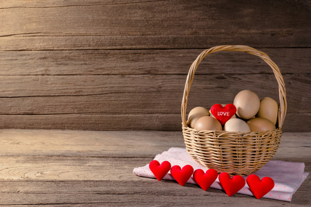 eggs in a wicker basket with heart-shaped on wooden tableの写真素材