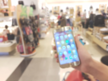 hand holding mobile smart phone in shopping mall,blur backgroundの写真素材