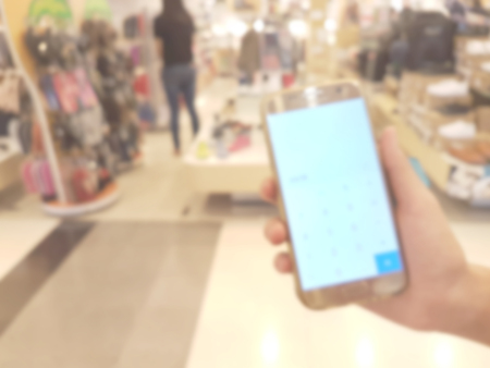 hand holding mobile smart phone in shopping mall,blur backgroundの写真素材