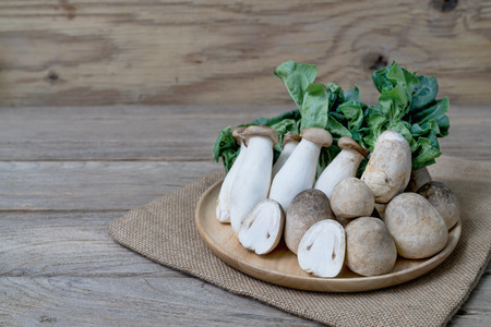 Straw mushroom and king oyster mushrooms on wooden tableの写真素材