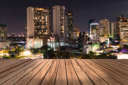 top wood desk with urban city night view blur background,wooden tableの写真素材
