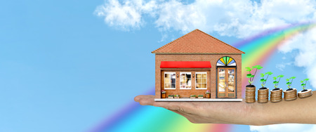 hand holding a store with piles of coins and tree on white blue sky background ,Lucky economic growth conceptの写真素材