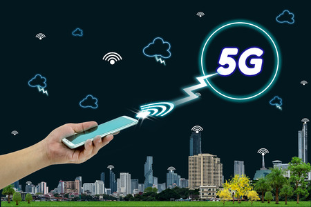 hand holding mobile smart phone with cityscape,5G network interface and icon concept