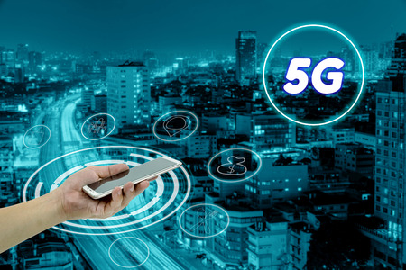 hand holding mobile smart phone with cityscape,5G network interface and icon concept