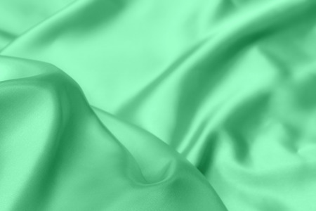 green satin fabric texture soft blur backgroundの写真素材