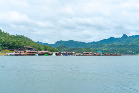 Floating resort and inflatable water park on a calm lake with lush green mountains under a cloudy...