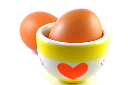 Eggs and ceramic cup on white backgroundの写真素材