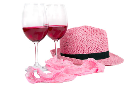 two glasses of red wine on a white background near pink panties and hatの写真素材