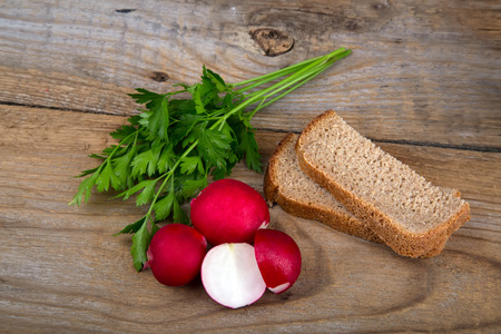 Fresh red radish parsley and bread on old wooden surfaceの写真素材