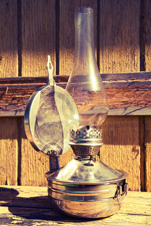 old kerosene lamp stands on wooden surface, outdoors, toningの写真素材