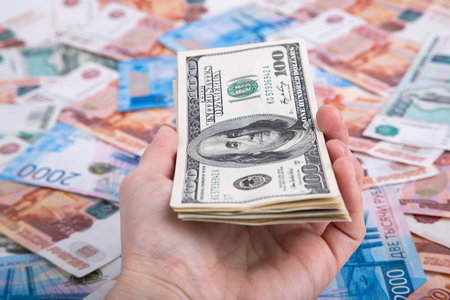 A bundle of dollars in his hand on the background of Russian moneyの写真素材