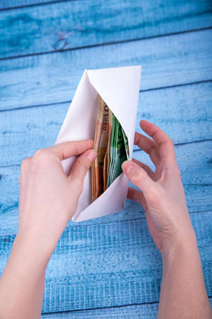 A woman's hand holds an envelope with money. The concept of saving money.