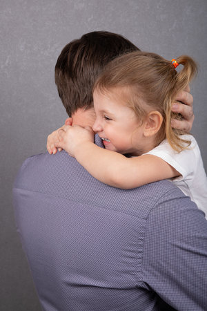 A little girl hugs her dad and smilesの写真素材