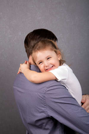 A little girl hugs her dad and smilesの写真素材