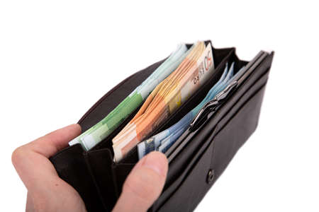A man is holding an open wallet with money on a white background close-up