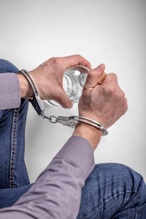 women's handcuffed hands hold dollars on a dark wooden background