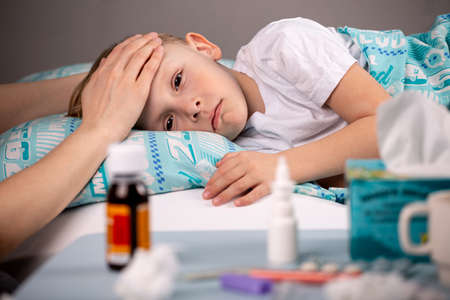 Medications, a thermometer, pills against the background of a sick child lying in bed, Focus on a table with medicines.の写真素材