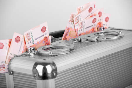 Handcuffs lying on a briefcase with money sticking out of it