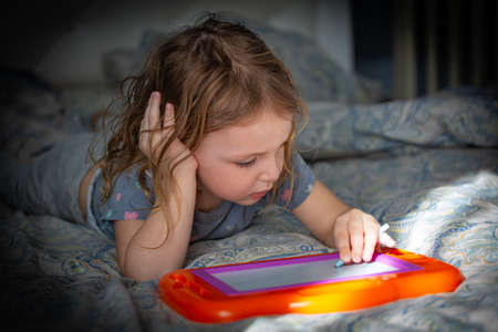 A little girl washes her hands with soap under the tapの写真素材