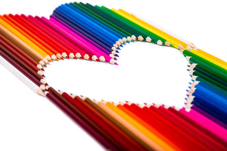 Multicolored pencils laid out in the shape of a heart on a white background