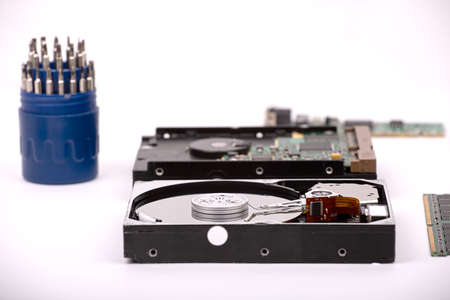A disassembled hard drive against the background of a drive, a set of tools and RAM modules