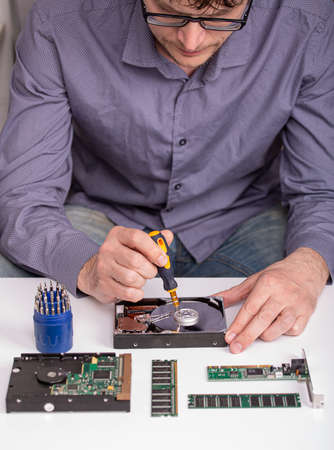 The master repairs the disassembled hard disk on the desktop next to the RAM modules, the board and...