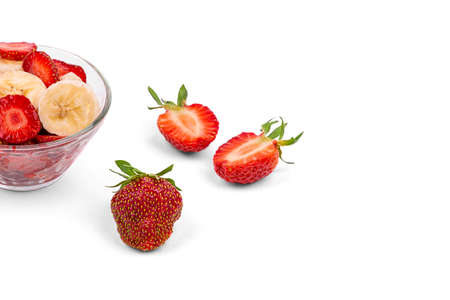 Fresh strawberries, a plate with sliced strawberries and a banana, on a white background close-upの写真素材