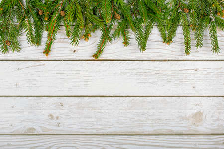 Christmas frame made of snow-covered fir branches with cones on a light wooden background. copy spaceの写真素材
