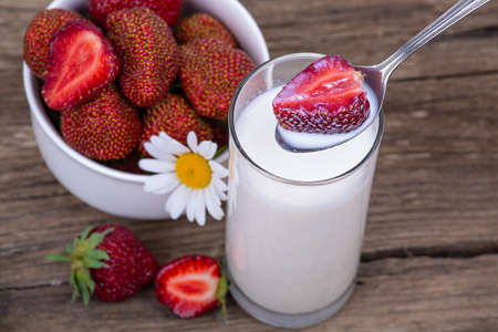 Ripe strawberries in milk, a plate with strawberries on a wooden background, close-upの写真素材