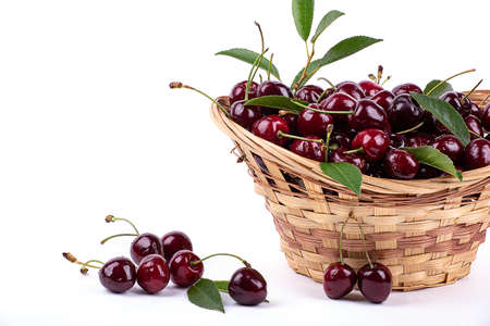 Ripe cherry in drops of water, in a wicker basket, isolated on a white background, close-upの写真素材