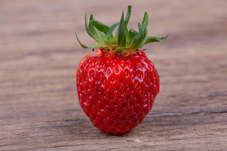 Ripe strawberry berry on a wooden background, macro photographyの写真素材
