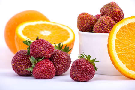 Ripe strawberries and a juicy piece of orange on a white background close-upの写真素材