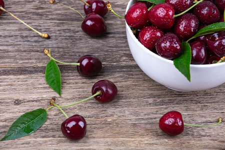 Ripe cherry in water drops on a wooden background, close-upの写真素材