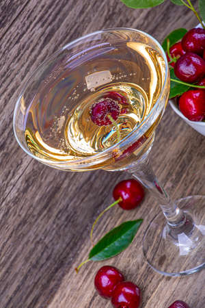 Cherry in a champagne glass, on an old wooden background, close-upの写真素材