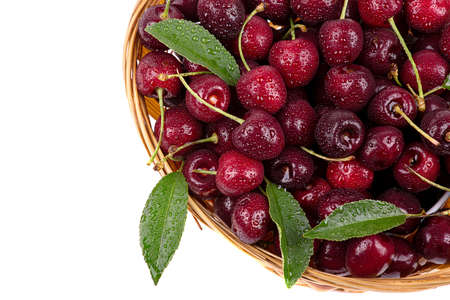 Ripe cherry in drops of water, in a wicker basket, isolated on a white background, close-upの写真素材