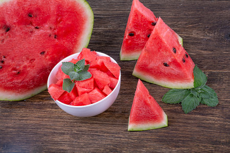 Slices, slices and half of a ripe juicy watermelon, close-up on a wooden backgroundの写真素材