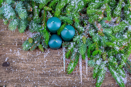 background for a gift card. New Year's composition of snow-covered fir branches with cones, icicles and green candles. copy spaceの写真素材