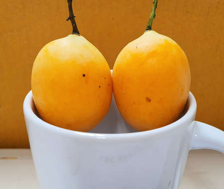 Close up picture of yellow sweet Marian plums in white mug