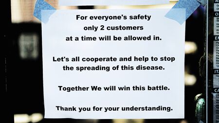 Sign on business limiting customers during coronavirus quarantineの写真素材