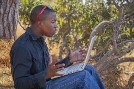 Smiling african student using a laptop outsideの写真素材