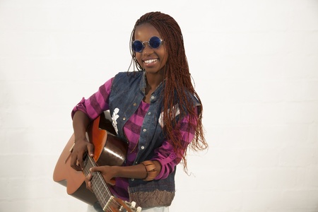 Beautiful african woman playing guitar against white backgroundの写真素材