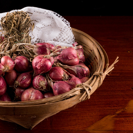 Group of red onions in a wooden basket on the table.の写真素材