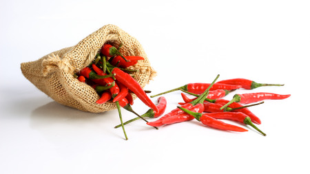 Red chili peppers in a sack bag on white background.の写真素材