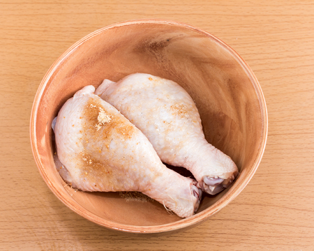 Raw chicken wings in bowl on wooden tableの写真素材