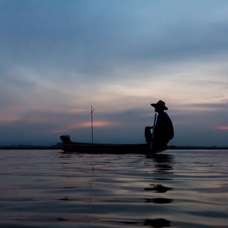 silhouette of fishermen using nets to catch fish at the lake.の写真素材