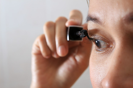 Woman eye with long eyelashes and mascara brush.