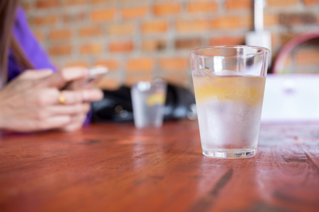 Water in a glass with ice placed on wooden table.の写真素材