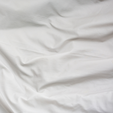 Creased white cloth material fragment as a background.の写真素材