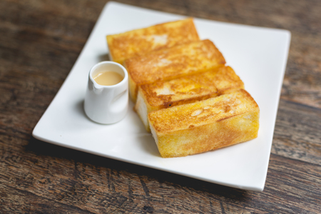 Toast bread served with sweet syrup,toast butter served with sweetened condensed milk on wooden...